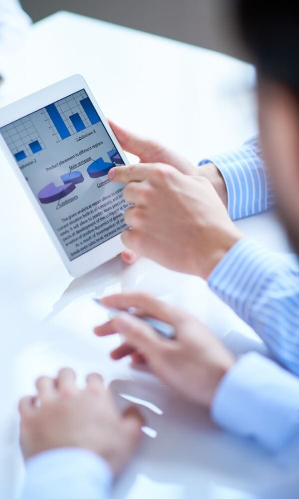 A group of business people looking at a tablet with graphs on it.