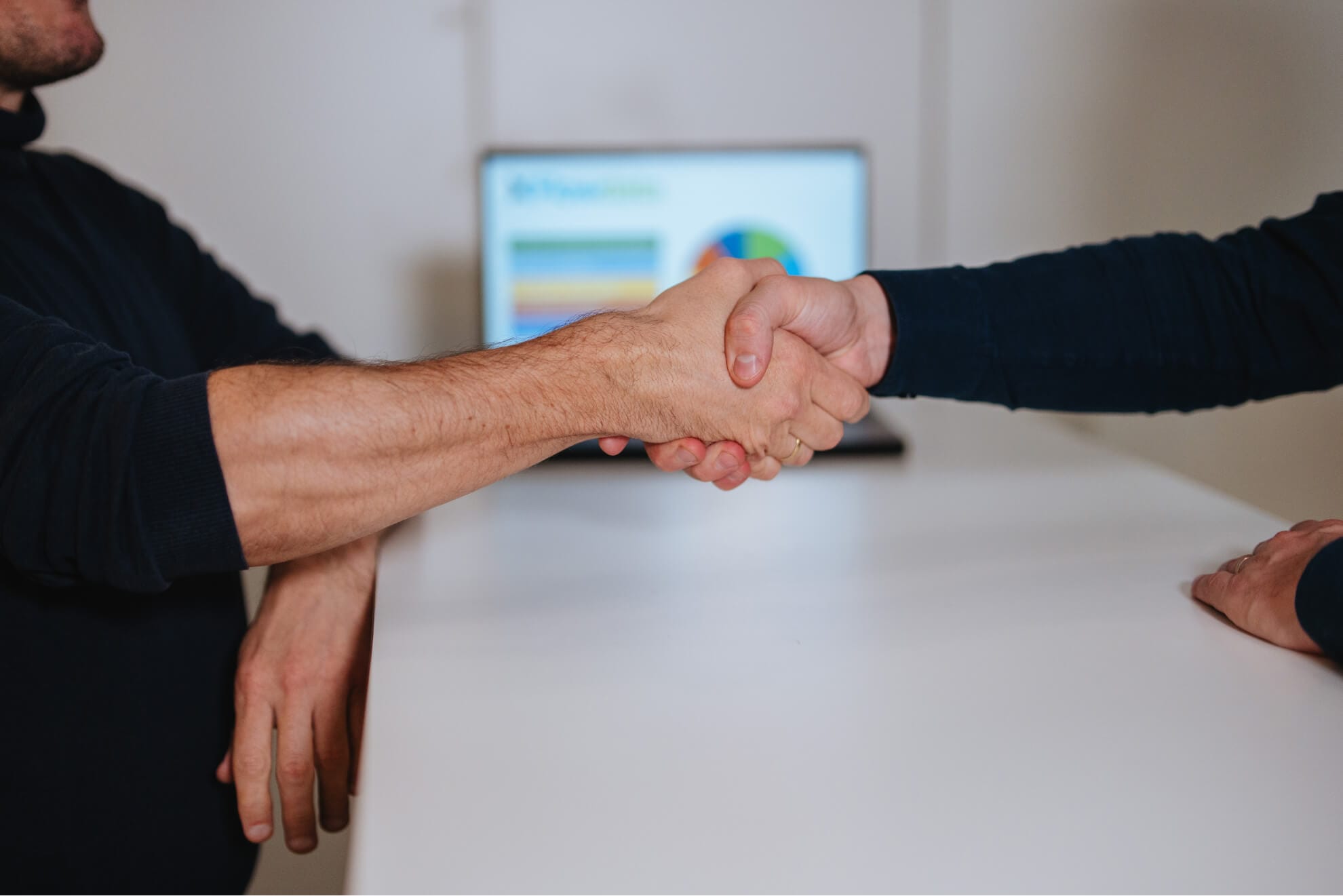 Two men shaking hands at a desk.