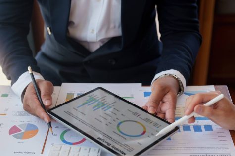 Two business people looking at graphs on a tablet.