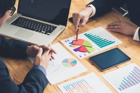 Two business people looking at graphs on a table.